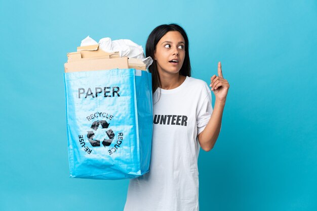 Junge Frau, die einen Recyclingbeutel voll Papier hält und eine Idee denkt, die den Finger nach oben zeigt