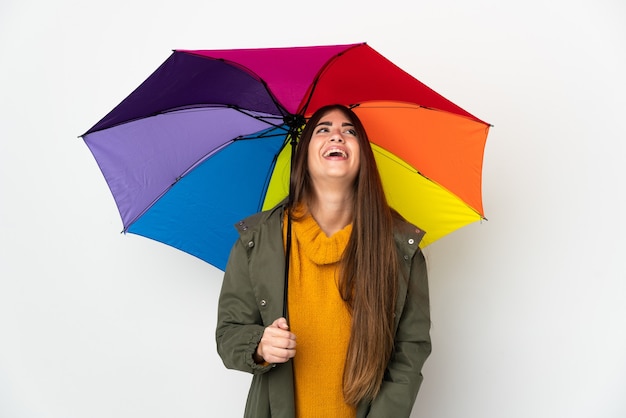 Junge Frau, die einen Regenschirm lokalisiert auf weißem Wandlachen hält