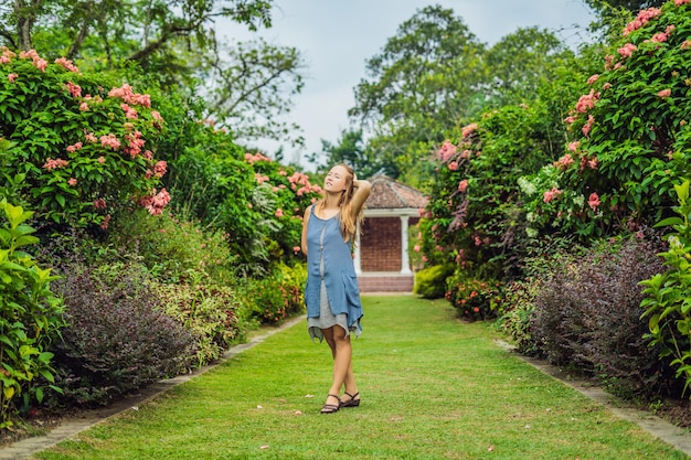 Junge Frau, die einen schönen blühenden Garten genießt