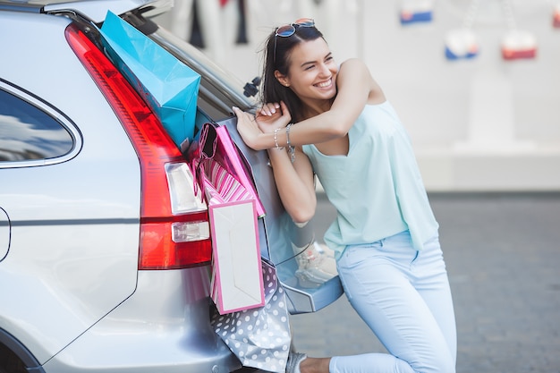 Junge Frau, die Einkaufstaschen in ihr Auto setzt