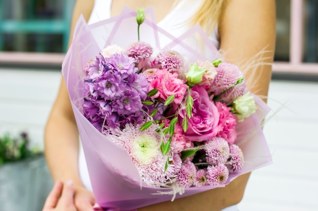 Junge Frau, die empfindlichen Blumenstrauß von Blumen auf der Straße nahe Blumenladen hält