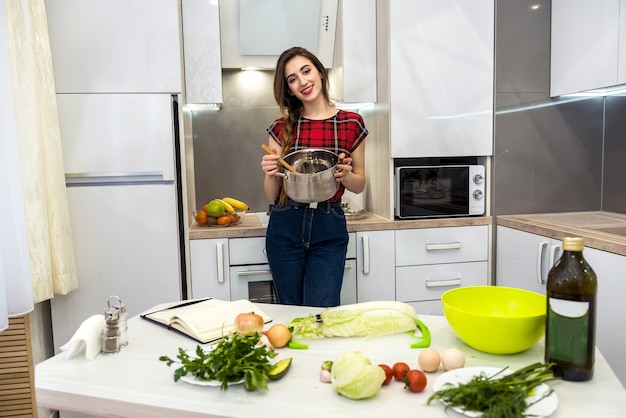 Junge Frau, die Essen in einem Topf in der Küche kocht.