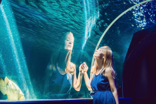 Junge Frau, die Fische in einem Tunnelaquarium betrachtet