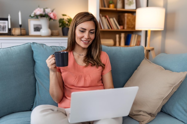 Junge Frau, die Forschungsarbeit für ihr Unternehmen macht Lächelnde Frau sitzt auf dem Sofa und entspannt sich, während sie eine Online-Shopping-Website surft Glückliches Mädchen surft im Internet in der Freizeit zu Hause