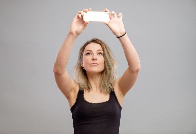 Junge Frau, die Fotos durch ihr Telefon macht