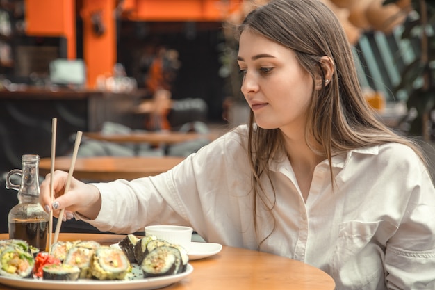 Junge Frau, die frisches Sushi isst und genießt