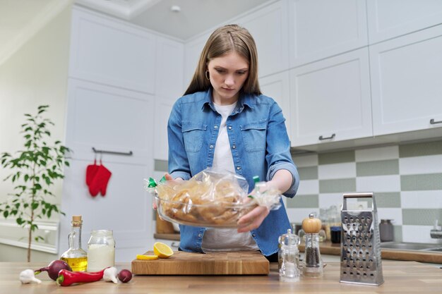 Junge Frau, die gebackenes Hähnchen in Backhülse mit Gewürzen kocht