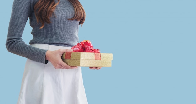 Junge Frau, die Geschenkbox, auf Blau hält