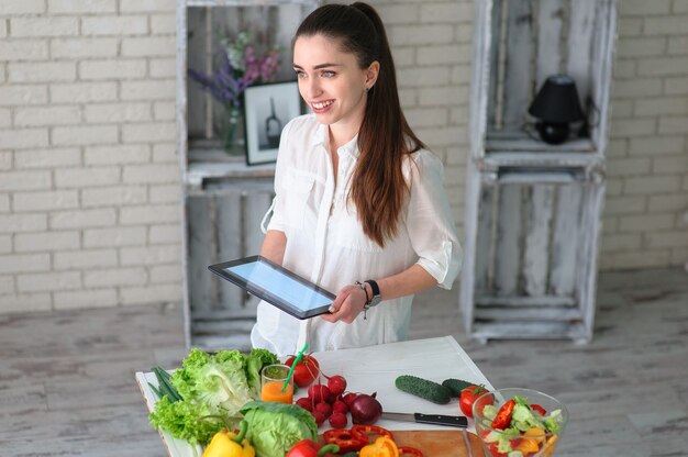 Foto junge frau, die gesunden gemüsesalat kocht