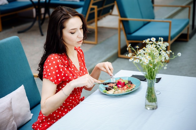 Junge Frau, die gesundes Frühstück im Resort-Café im Freien isst und unterwegs ist?