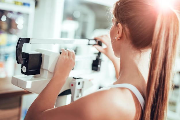 Junge Frau, die Gewicht im Fitnessstudio misst.