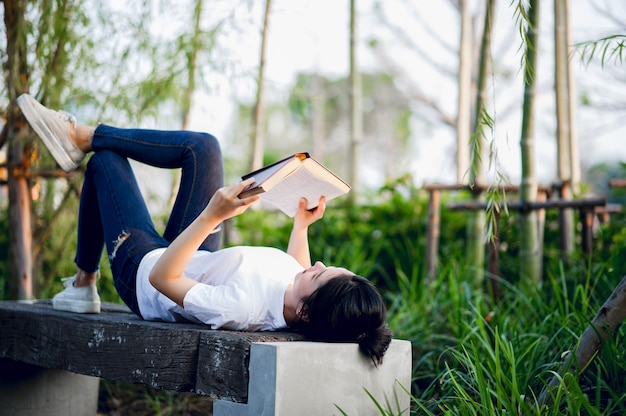 Junge Frau, die glücklich das Buch in der Natur liest