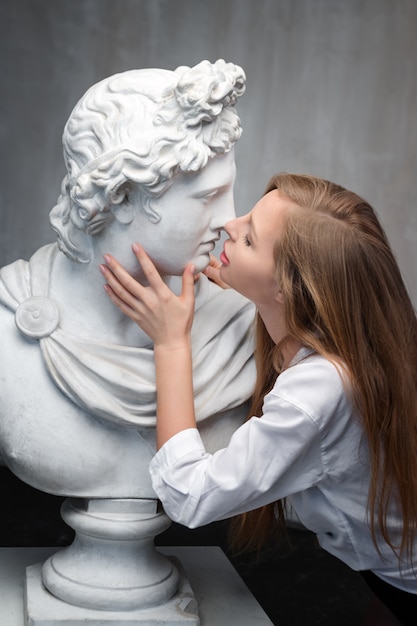 Junge Frau, die Gott Apollo Büste Skulptur küsst.