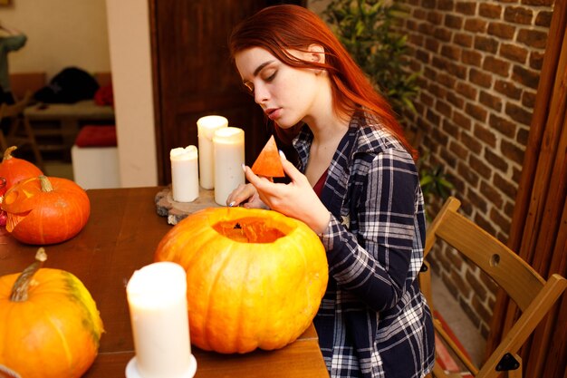 Junge Frau, die Halloween-Kürbis Jack-o-Laterne macht. Weibliche Hände, die Kürbisse mit Messer schneiden.