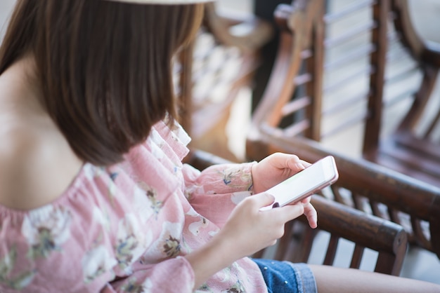 Junge Frau, die Handy sitzt und verwendet