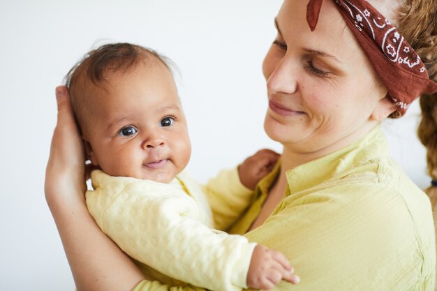 Foto junge frau, die ihr baby auf händen hält und sie bewundert