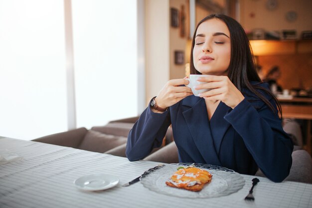 Junge Frau, die ihre Tasse Kaffee genießt