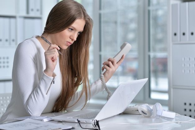 Junge Frau, die im Büro mit Laptop arbeitet