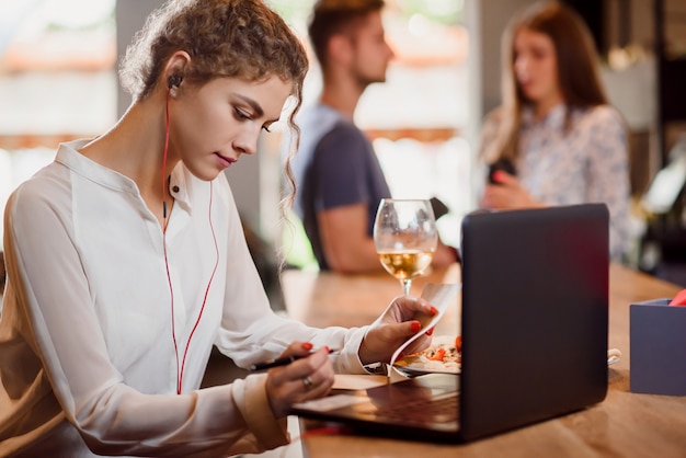 Junge Frau, die im Café sitzt und mit Notizbuch arbeitet.