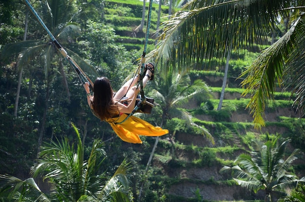 Junge Frau, die im Dschungelregenwald von Bali Indonesien schwingt