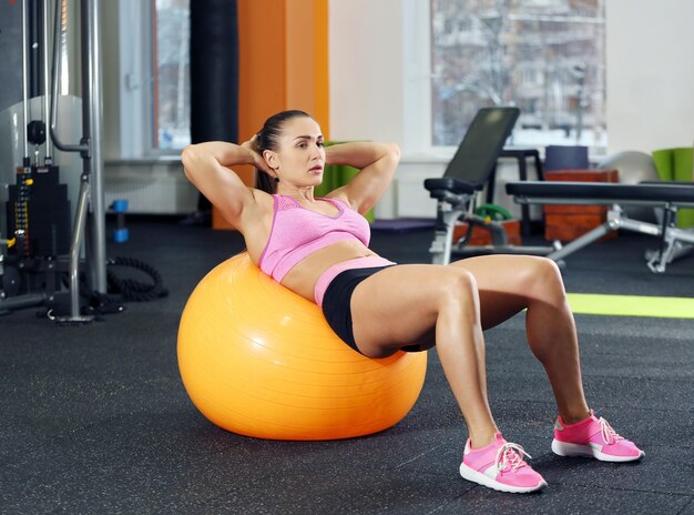 Junge Frau, die im Fitnessstudio mit Ball trainiert