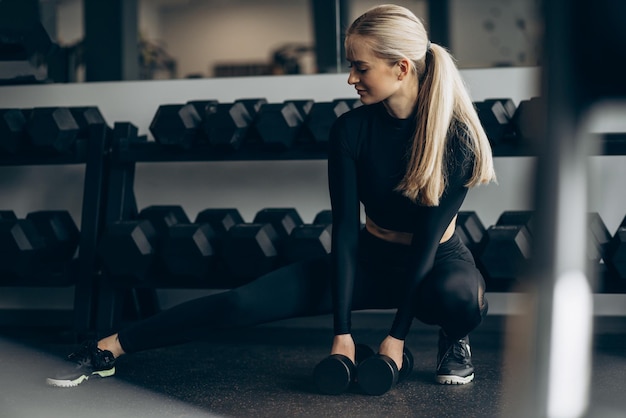 Junge Frau, die im Fitnessstudio mit Hanteln trainiert