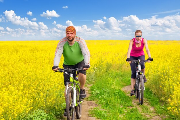 Junge Frau, die im gelben Blumenfeld radfährt