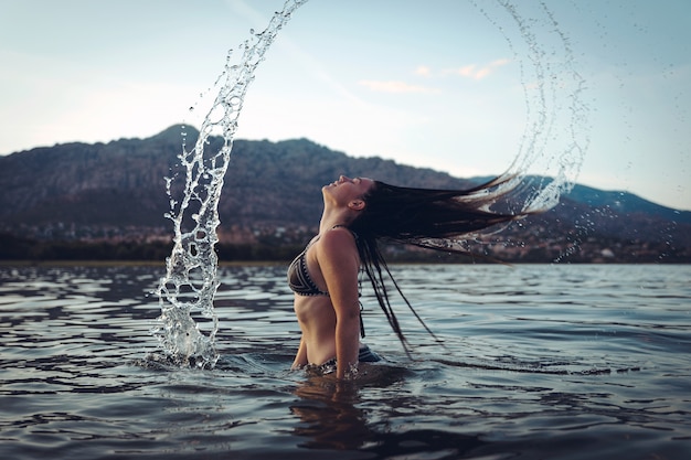 Junge Frau, die im See bei Sonnenuntergang schwimmt