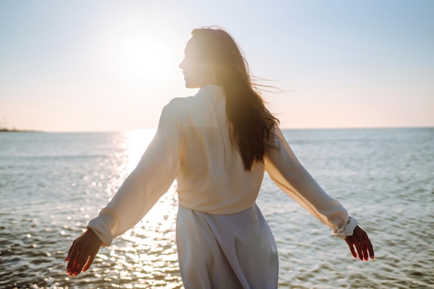 Junge Frau, die im Sonnenuntergang am Strand spazieren geht Sommerzeit Travel Weekend Lifestyle-Konzept