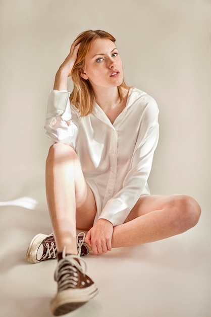 Junge Frau, die im Studio im weißen Hemd sitzt