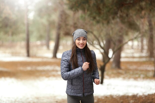 Junge Frau, die im Winterpark joggt