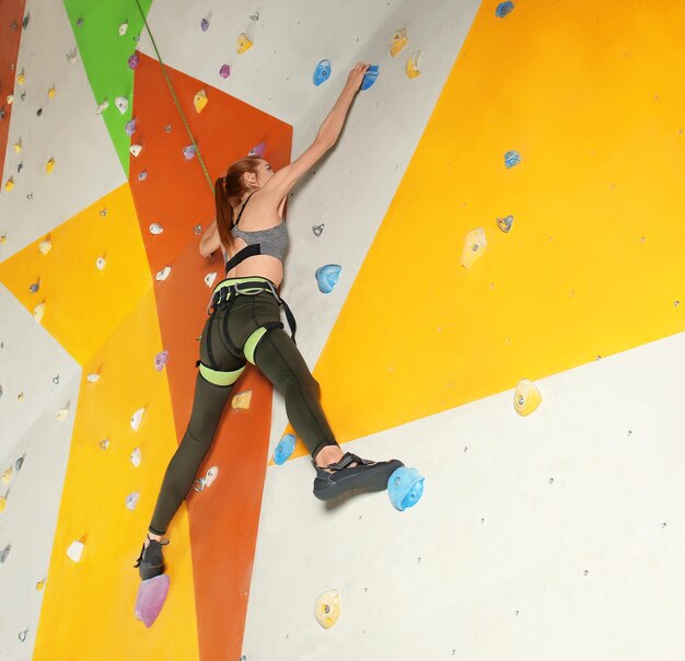 Junge Frau, die in der Kletterhalle trainiert