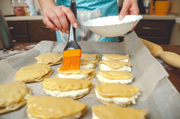 Junge Frau, die in der Küche kocht, bereitet die Kuchen zum Backen vor