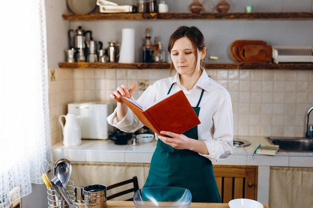 Junge Frau, die in der Küche mit Rezeptbuch steht. Kochen zu Hause Konzept, Lifestyle.