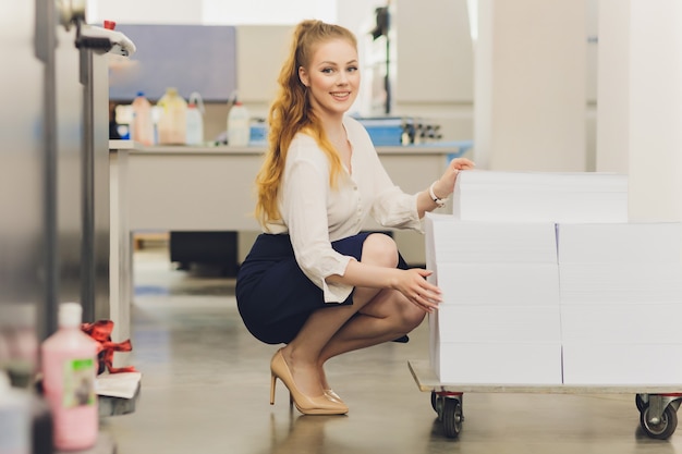 Junge Frau, die in Druckerei arbeitet. Druckerpresse.