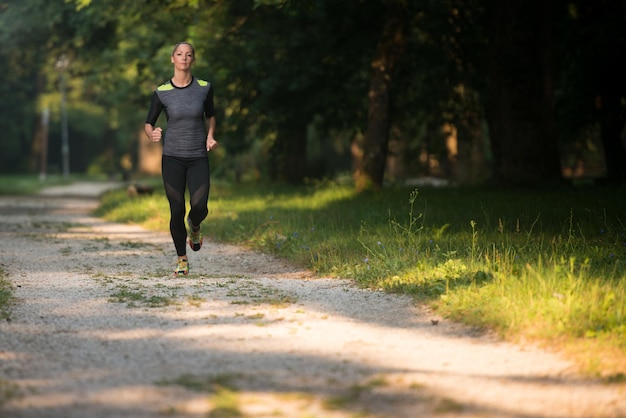 Junge Frau, die in einem bewaldeten Waldgebiet läuft - Training und Training für Trailrun-Marathon-Ausdauer - Fitness-Konzept für einen gesunden Lebensstil