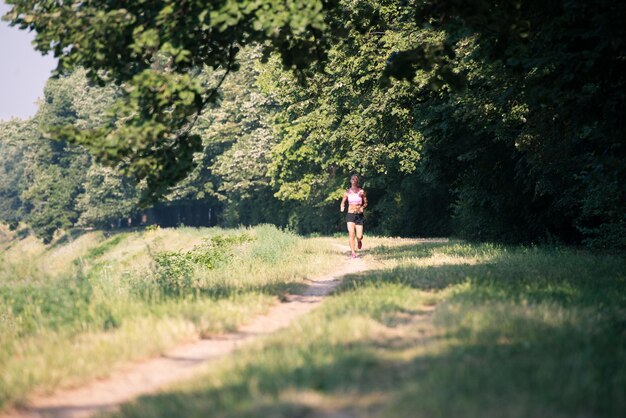 Junge Frau, die in einem bewaldeten Waldgebiet läuft - Training und Training für Trailrun-Marathon-Ausdauer - Fitness-Konzept für einen gesunden Lebensstil