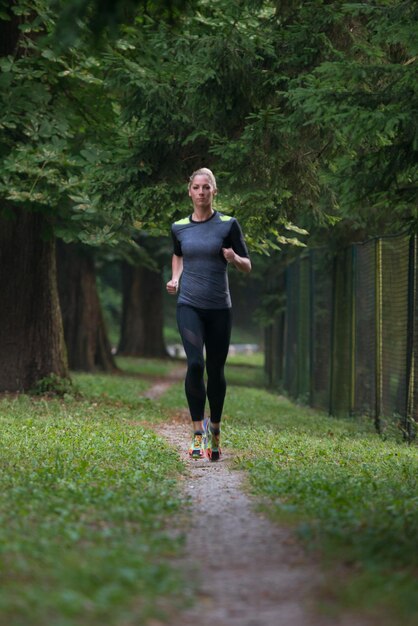 Junge Frau, die in einem bewaldeten Waldgebiet läuft - Training und Training für Trailrun-Marathon-Ausdauer - Fitness-Konzept für einen gesunden Lebensstil