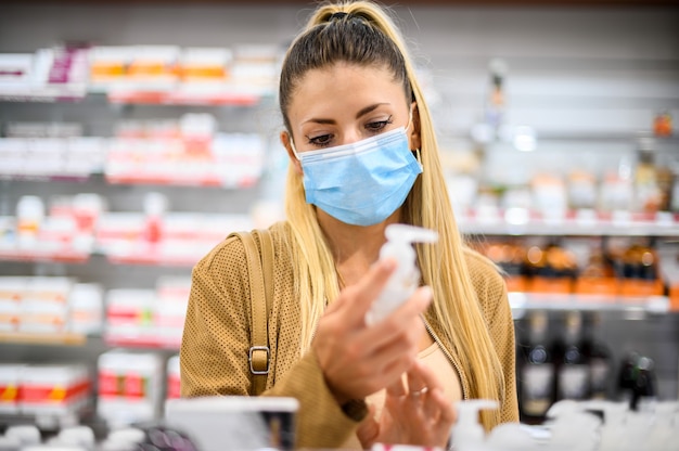 Junge Frau, die in einem Geschäft nach einem Produkt sucht, das aufgrund von Coronavirus eine Maske trägt