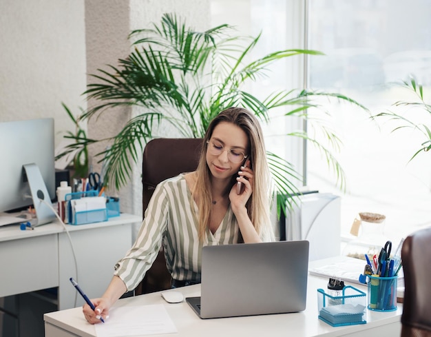 Junge Frau, die in ihrem Büro an einem Computer arbeitet