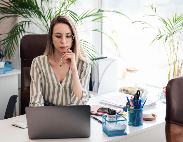 Junge Frau, die in ihrem Büro an einem Computer arbeitet