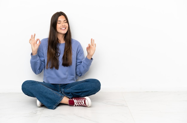 Junge Frau, die in Zen-Pose auf dem Boden sitzt