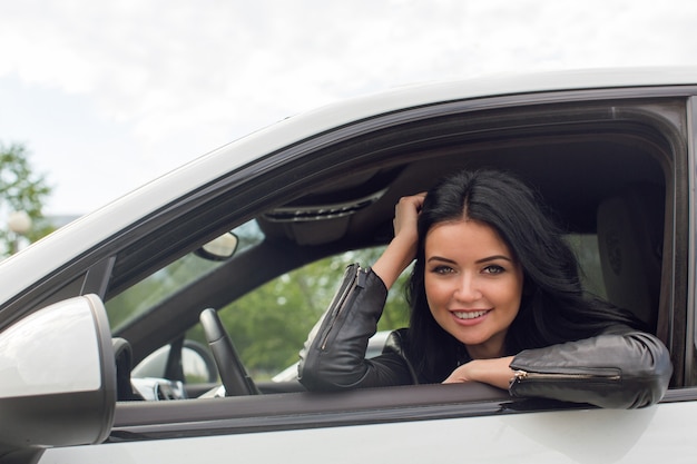 Junge Frau, die innerhalb des Autos lächelt an der Kamera sitzt