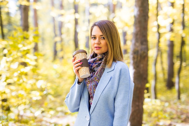 junge Frau, die Kaffee im Herbstpark trinkt