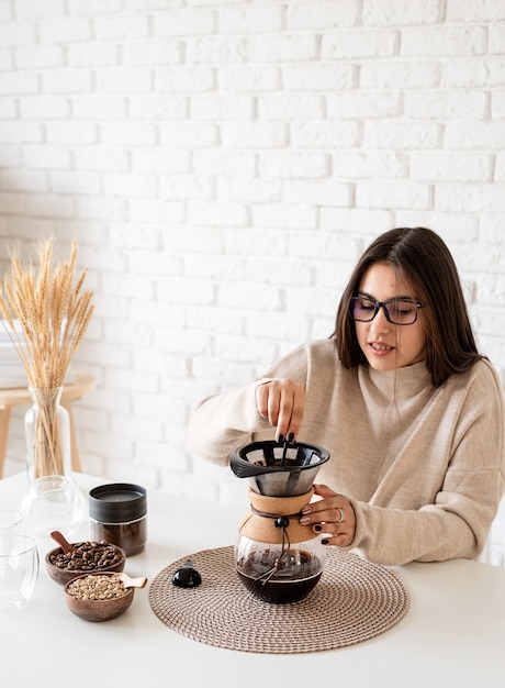 Junge Frau, die Kaffee im Kaffeemacher braut