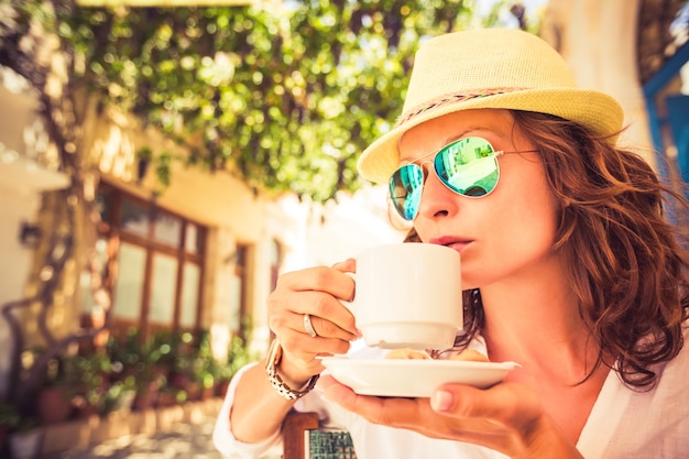 Junge Frau, die Kaffee im Sommercafé trinkt