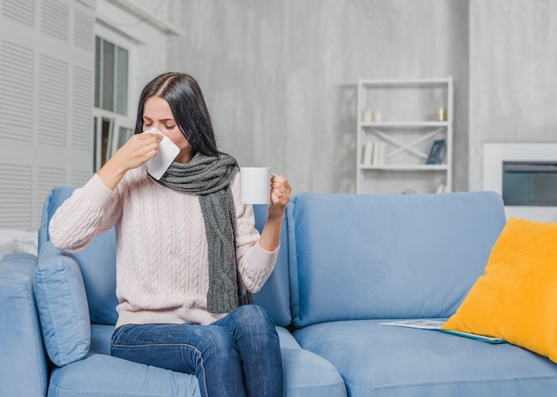 Junge Frau, die Kaffeetasse leidet unter Husten hält