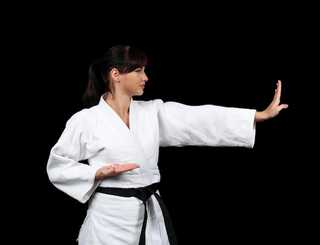 Junge Frau, die Karate auf dunklem Hintergrund praktiziert