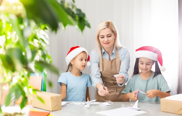 Junge Frau, die kleinen Töchtern hilft, Dekoration für Weihnachten zu machen