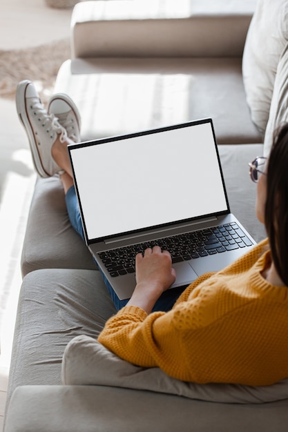 Junge Frau, die Laptop-Bildschirm leer, Modell, das auf Sofa zu Hause liegt